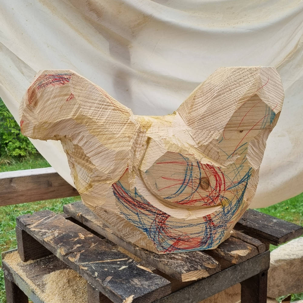 Erste Bearbeitungsphase einer Holzskulptur: Die Hühnerform wurde grob aus dem Holzblock herausgearbeitet.