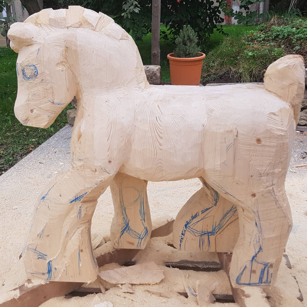 Fortgeschrittene Bearbeitung der Holzskulptur: Der Körper des Pferdes wurde weiter ausgearbeitet und die Form der Figur verfeinert.