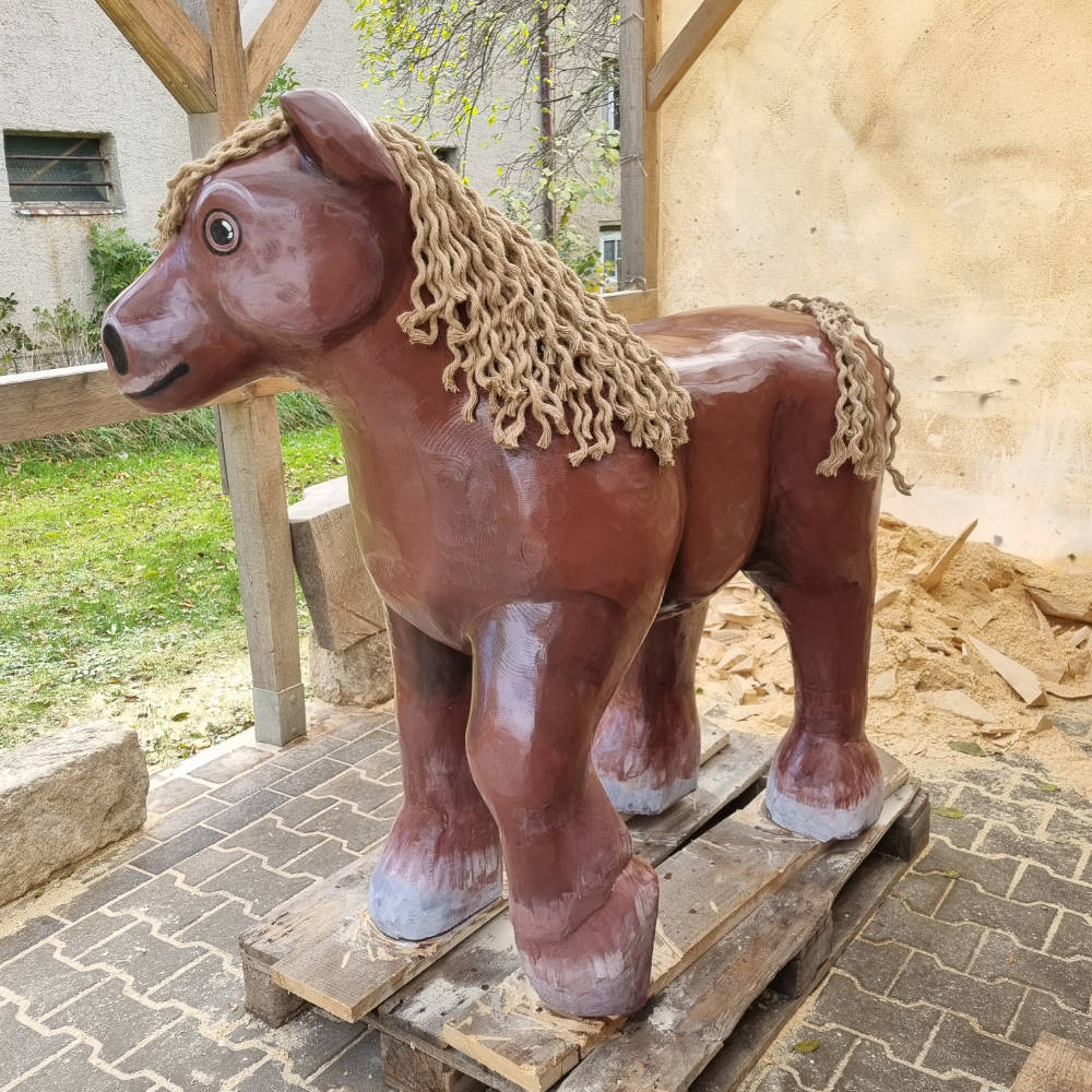 Ganzkörperansicht einer bemalten Pferdeskulptur aus Holz.
