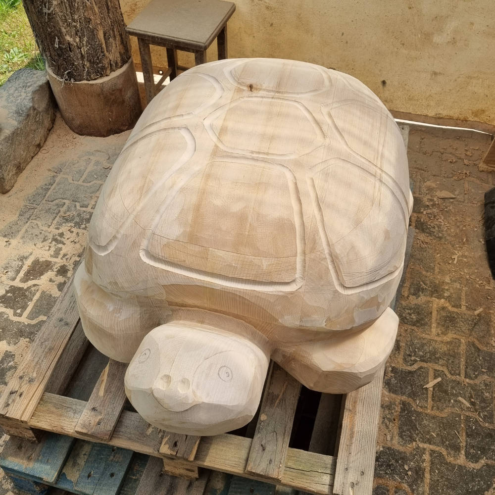 Frontalansicht einer weiter ausgearbeiteten Schildkrötenskulptur aus Holz mit verfeinerten Details.