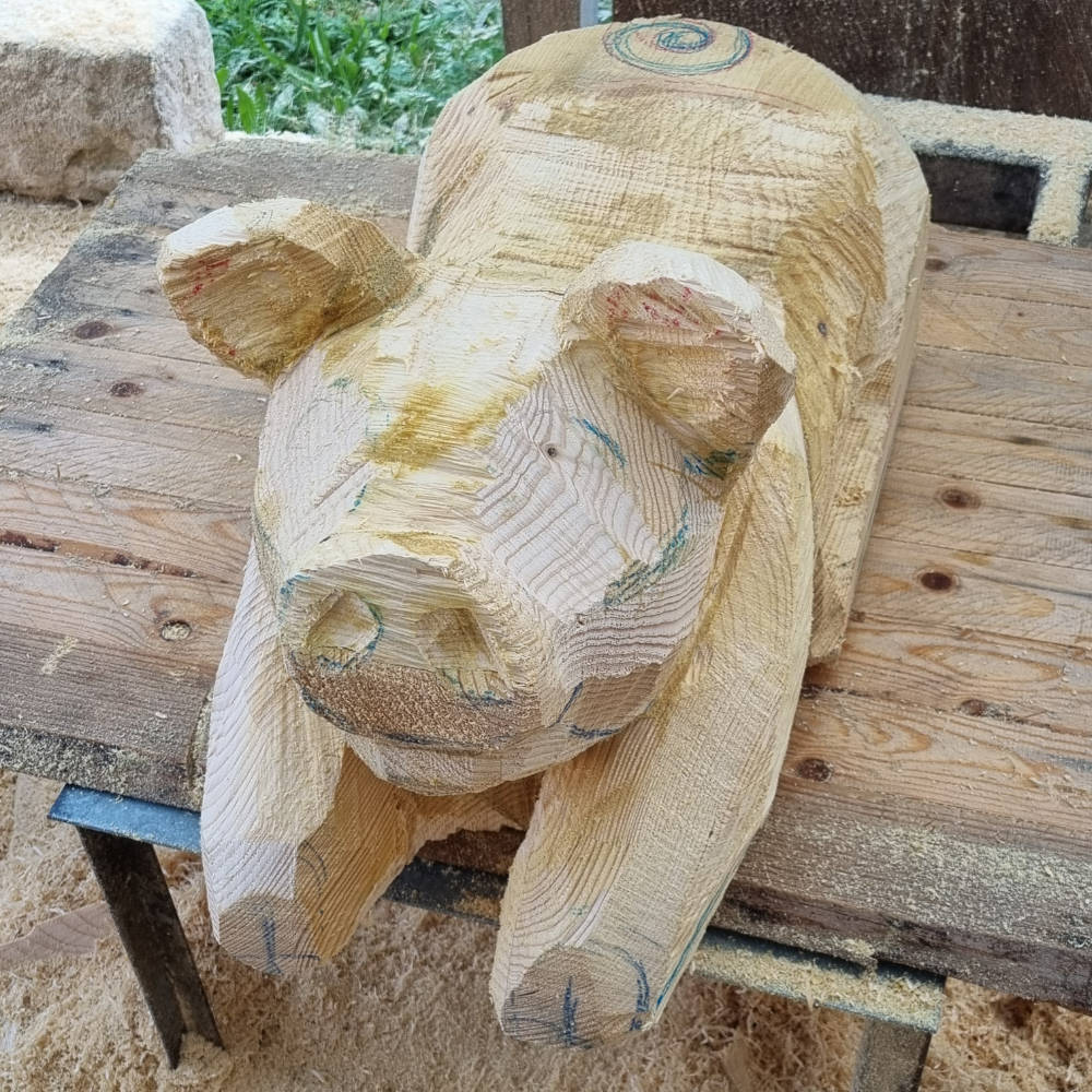 Weiter ausgearbeitete Schweinskulptur aus Holz mit verfeinerten Konturen.