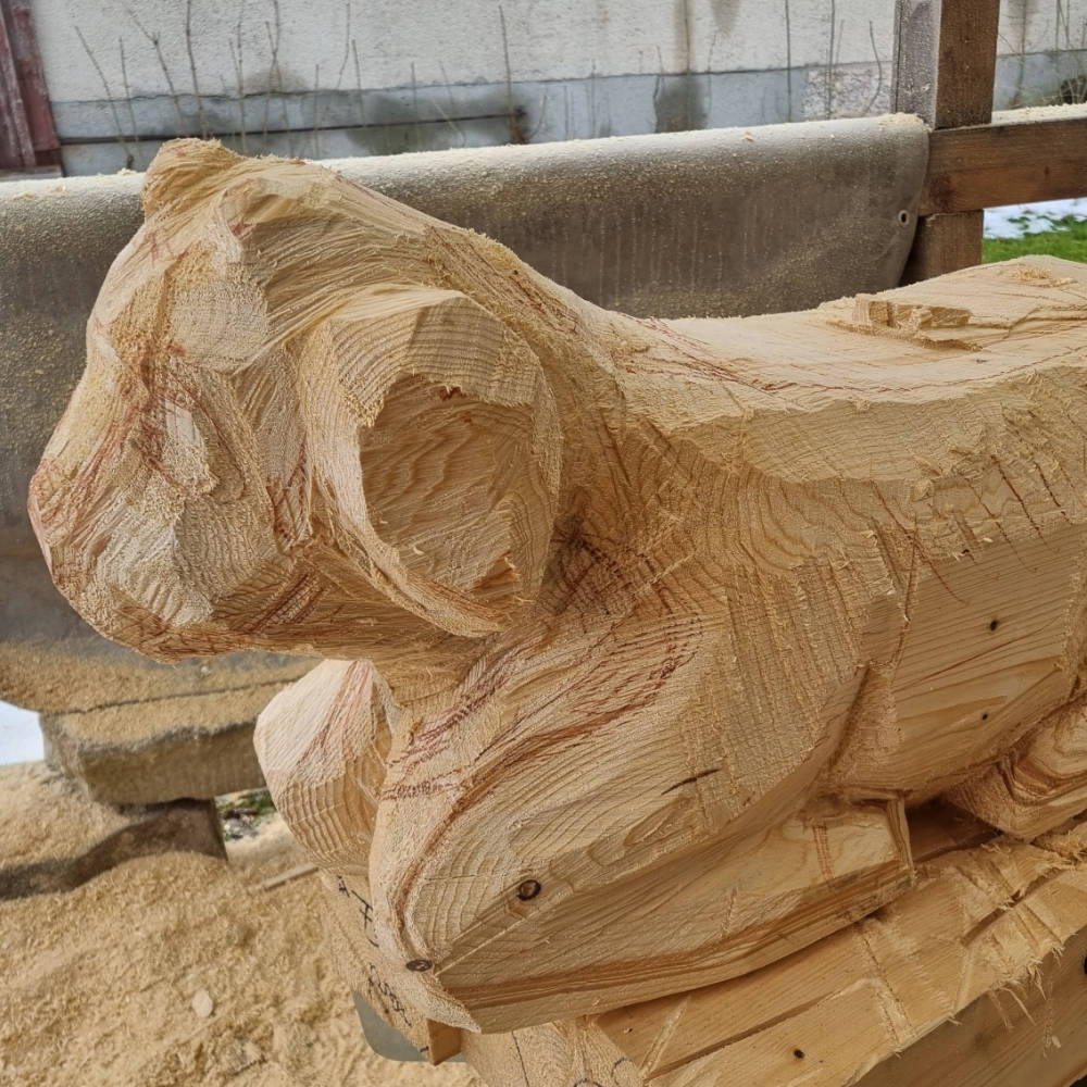 Grob aus dem Holzblock herausgesägte Form einer liegenden Ziege in der Werkstatt.