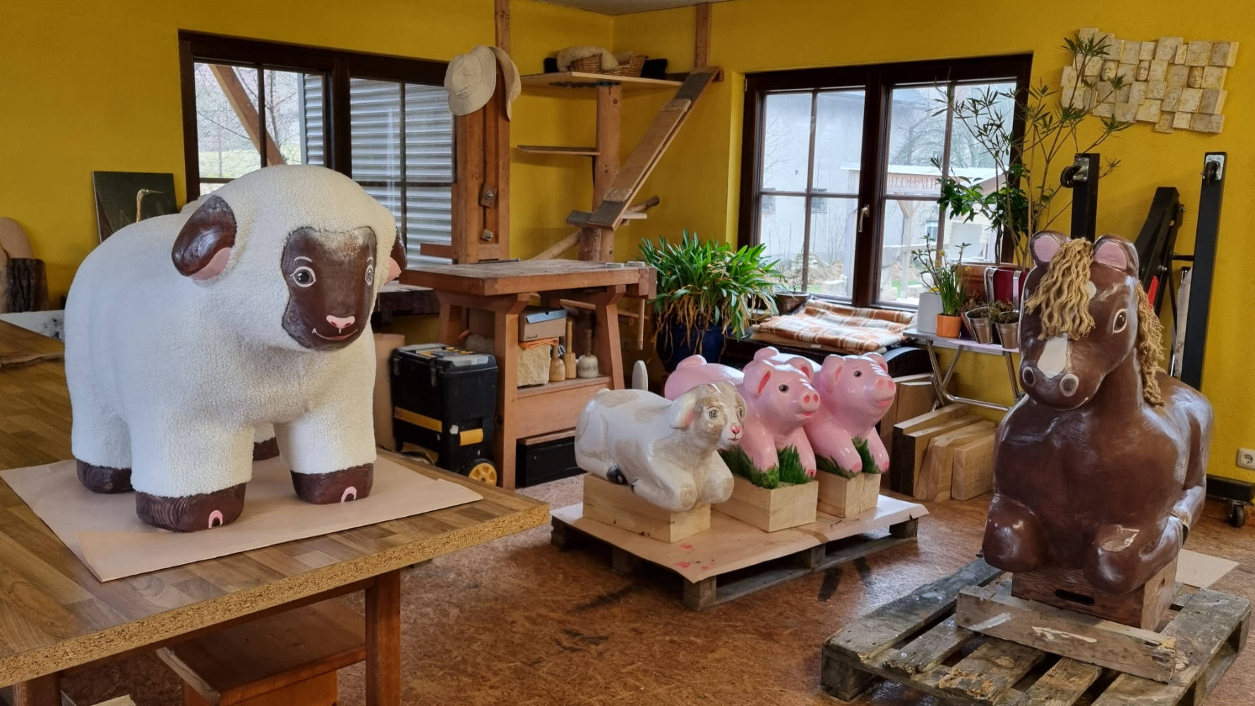 Werkstattraum mit mehreren handgefertigten Tierskulpturen aus Holz.