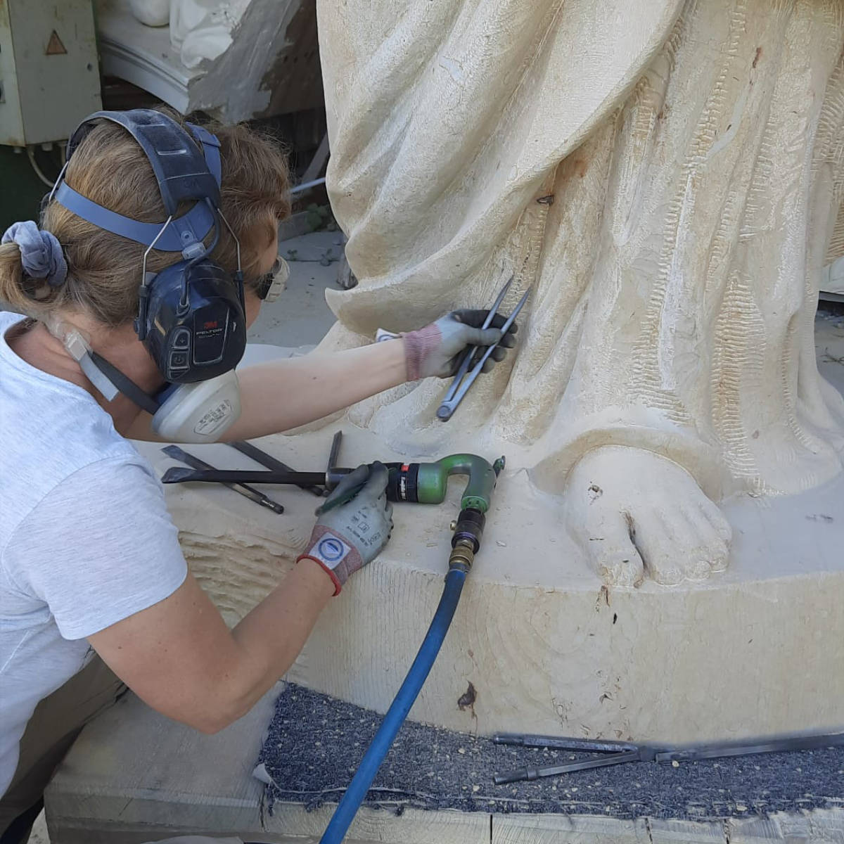 Juliane Uebe führt Feinarbeiten am Fuße der Sandsteinstatue des Propheten Hosea aus. 