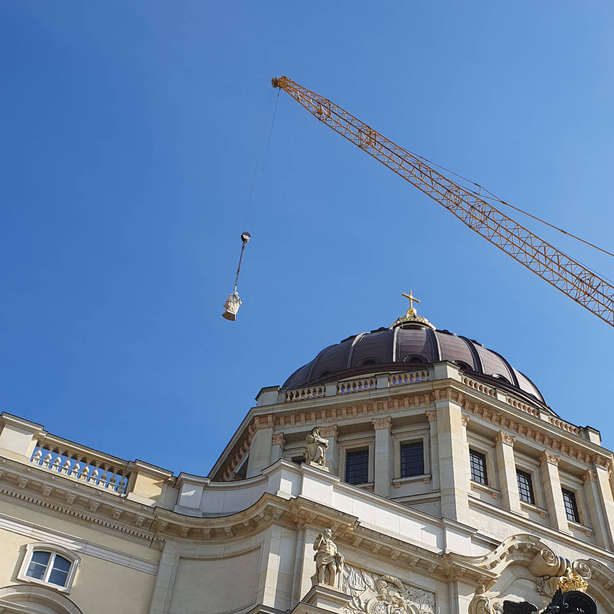 Eine Sandsteinstatue eines Propheten wird mit einem Kran an die Kuppel des Berliner Schlosses herangeführt.