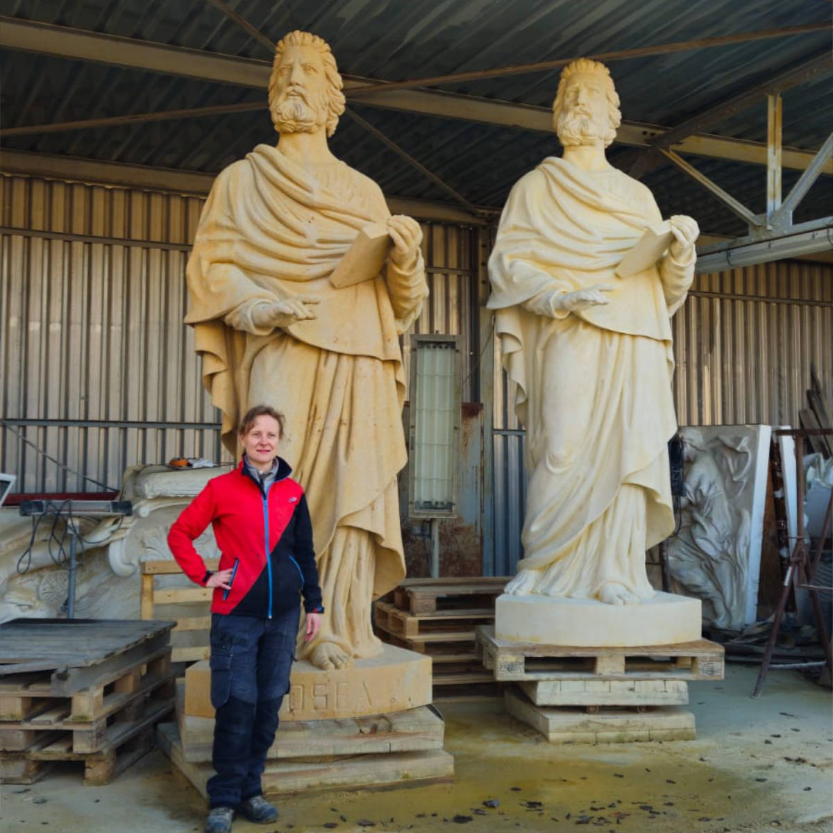 Bildhauerin Juliane Uebe neben der 3,3 Meter hohen Sandsteinstatue des Propheten Hosea als Größenvergleich.