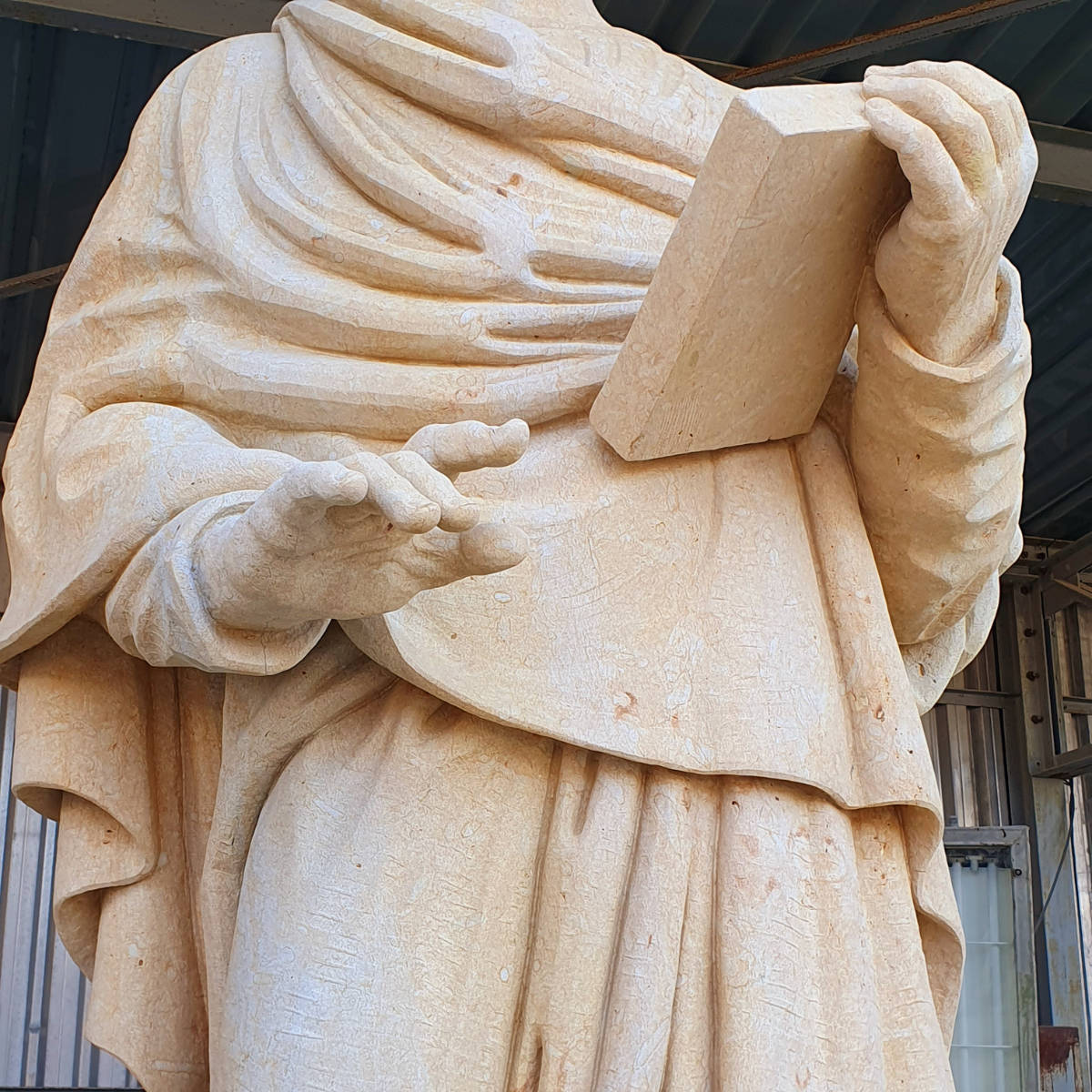 Detailaufnahme des Oberkörpers der Sandsteinstatue des Propheten Hosea mit ausgearbeitetem Gewand und ohne sichtbaren Kopfbereich.