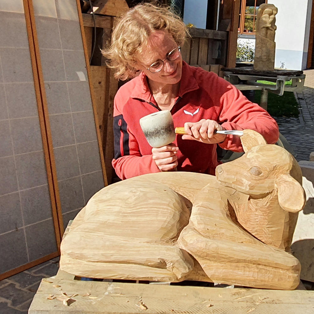 Juliane Uebe schnitzt ein Reh aus Holz in traditioneller Handarbeit.