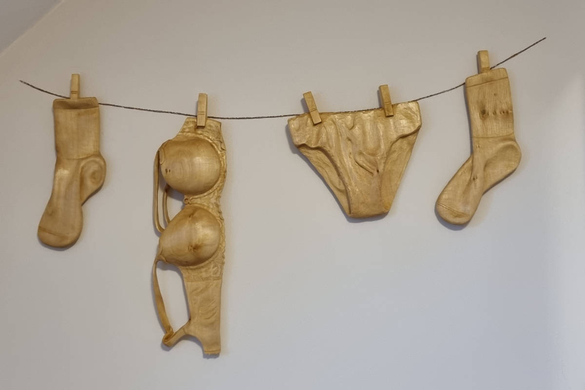 Künstlerisch gestaltete Unterwäsche aus Eichenholz, an einer Wäscheleine aufgehängt.